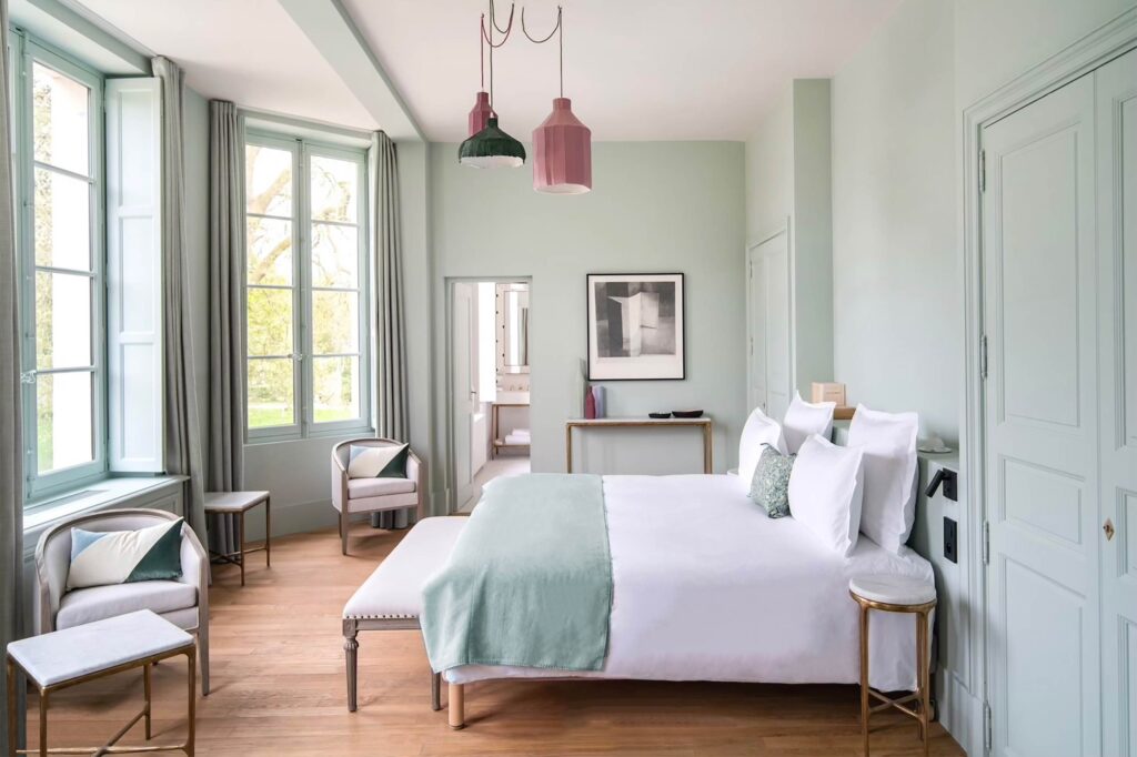 A breezy chic bedroom with light blue walls at Domaine de Primard Guainville.