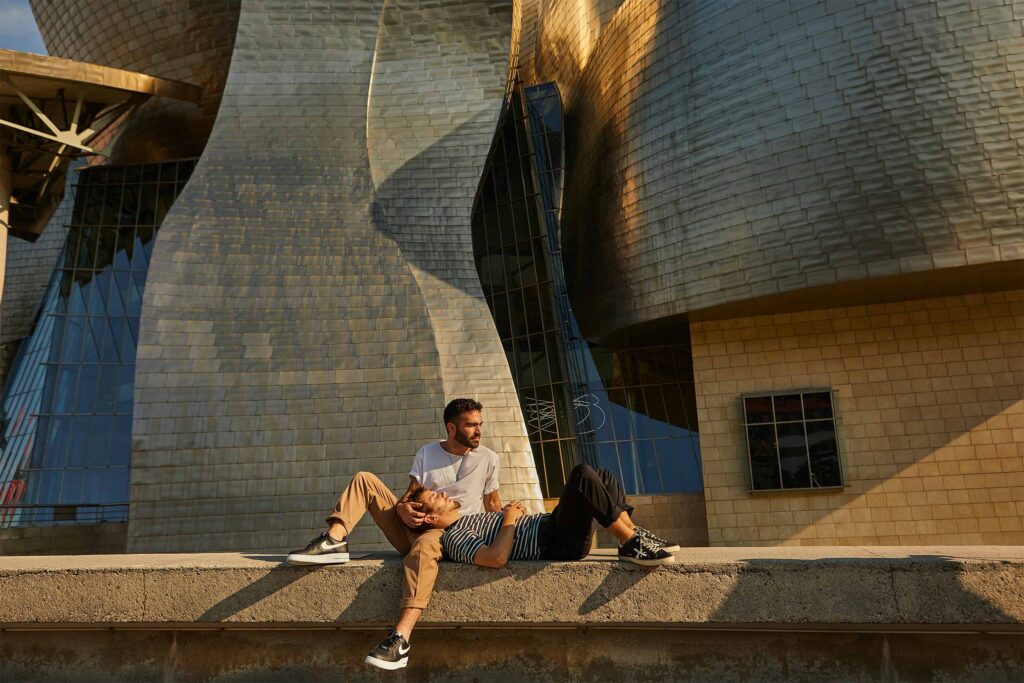 A traveller rests his head on the lap of his partner outside the Guggenheim Museum in Bilbao.