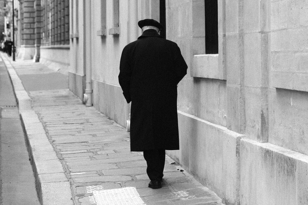 An elderly man walks down a street, one of many postcards from Paris, France