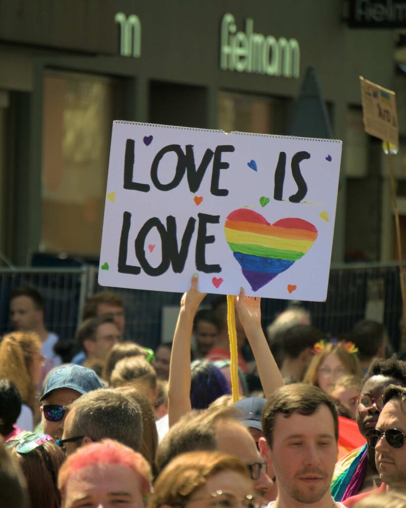 Placard at Pride saying "Love is Love" with a rainbow coloured heart for Pride Month