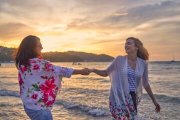 Two women at sunset on the beach, travel proud with Scott Dunn