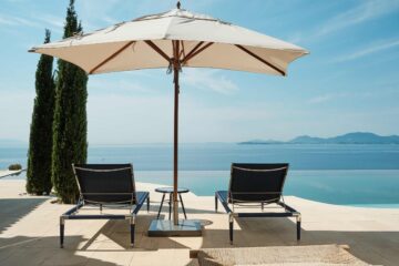 Sun loungers and umbrella by a private pool at the Ultima Corfu, overlooking the Ionian Sea