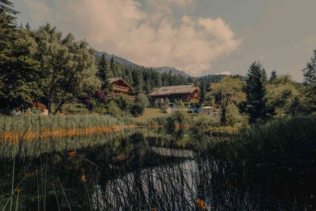 View over the lake, with greenery in the summer at Ultima Crans Montana by Ultima Collection