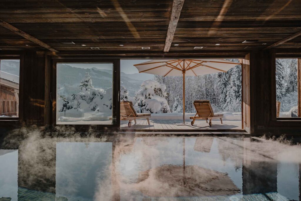 Steamy indoor pool overlooking mountains with snow outdoors at Ultima Megeve